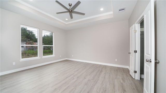 empty room featuring ceiling fan, a raised ceiling, crown molding, and light hardwood / wood-style flooring