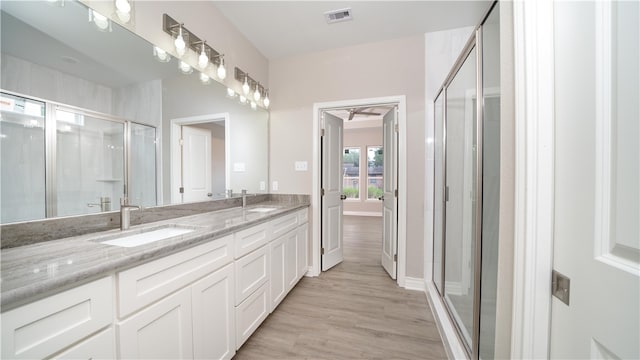 bathroom with wood-type flooring, vanity, and a shower with shower door