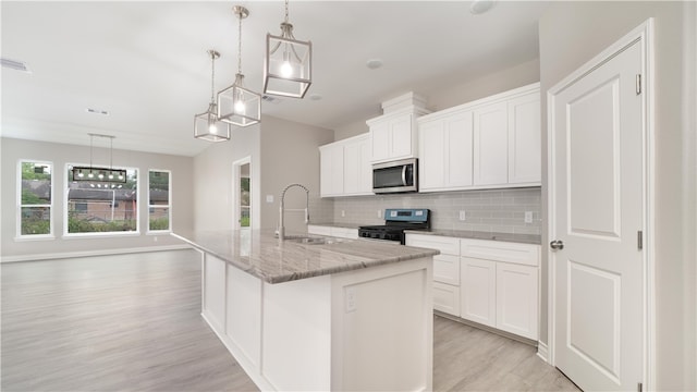 kitchen featuring black gas range, sink, an island with sink, decorative light fixtures, and white cabinets