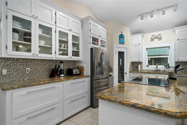 204 Bayshore Dr, Ingleside, TX 78362 - kitchen featuring stainless steel fridge with ice dispenser, decorative backsplash, glass insert cabinets, white cabinetry, and dark stone counters
