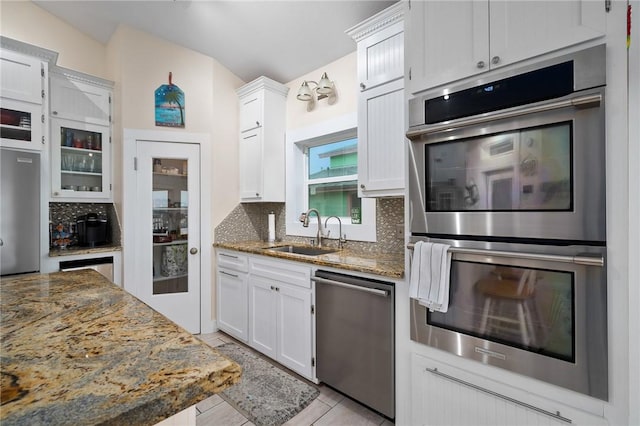 204 Bayshore Dr, Ingleside, TX 78362 - kitchen featuring appliances with stainless steel finishes, a sink, backsplash, dark stone countertops, and white cabinetry
