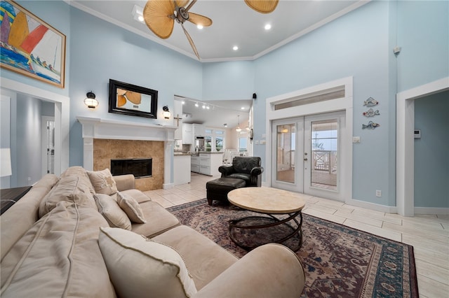 living room with french doors, a towering ceiling, a premium fireplace, ceiling fan, and crown molding