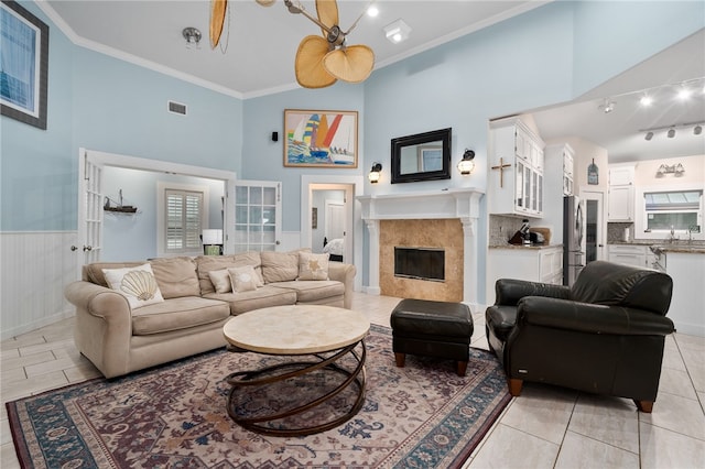 tiled living room featuring french doors, plenty of natural light, ceiling fan, crown molding, and a high ceiling