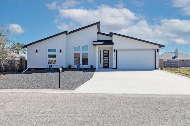 view of front of home featuring stucco siding, concrete driveway, a garage, and fence