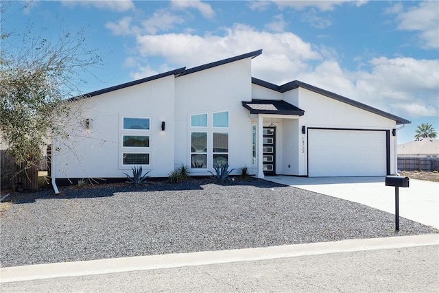 contemporary house with concrete driveway, a garage, and stucco siding