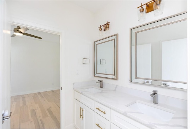 bathroom with a ceiling fan, double vanity, wood finished floors, and a sink