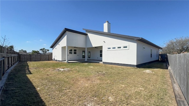 rear view of house featuring a ceiling fan, a fenced backyard, a chimney, a patio area, and a lawn