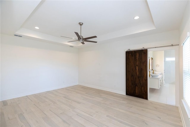 unfurnished room with visible vents, light wood-type flooring, and a raised ceiling