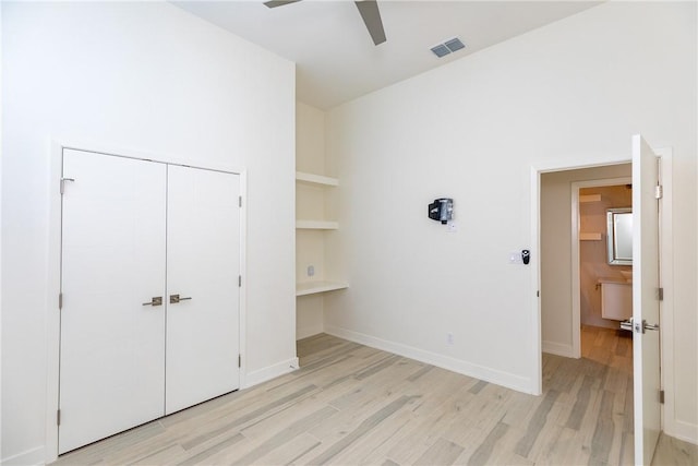 unfurnished bedroom with light wood-type flooring, visible vents, a ceiling fan, a closet, and baseboards