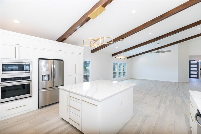 kitchen with a kitchen island, light stone countertops, white cabinets, stainless steel appliances, and modern cabinets