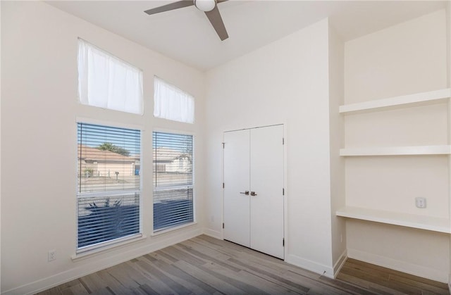 unfurnished bedroom with wood finished floors, baseboards, a closet, and ceiling fan