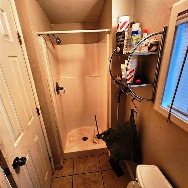 bathroom with walk in shower, tile patterned flooring, toilet, and a textured ceiling