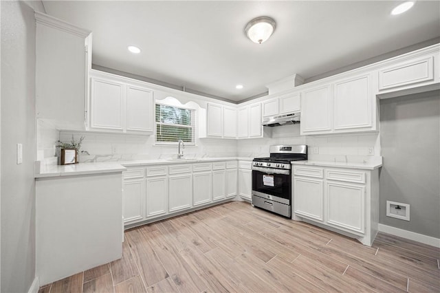 kitchen with sink, decorative backsplash, gas stove, and white cabinets