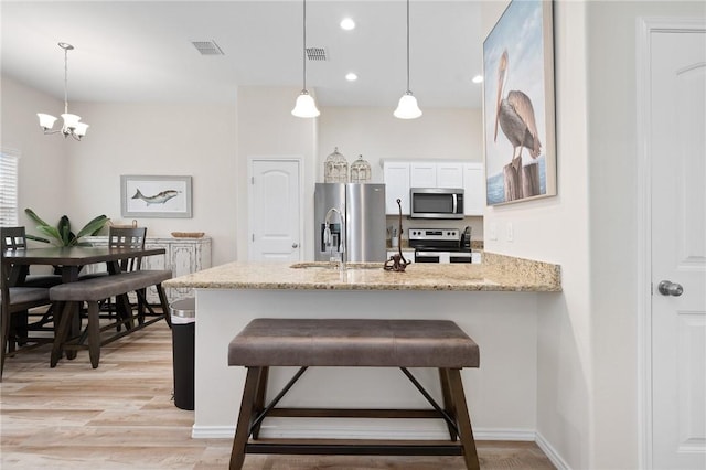 111 Great Chagos, Rockport, TX 78382 - kitchen featuring appliances with stainless steel finishes, a peninsula, white cabinetry, pendant lighting, and light stone countertops
