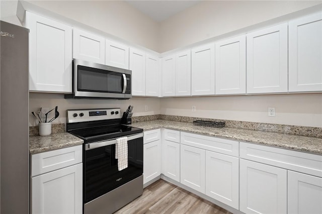 111 Great Chagos, Rockport, TX 78382 - kitchen with stainless steel appliances, white cabinetry, light wood-type flooring, and light stone countertops