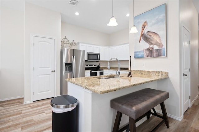 111 Great Chagos, Rockport, TX 78382 - kitchen with stainless steel appliances, a sink, light wood-style flooring, white cabinetry, and a peninsula