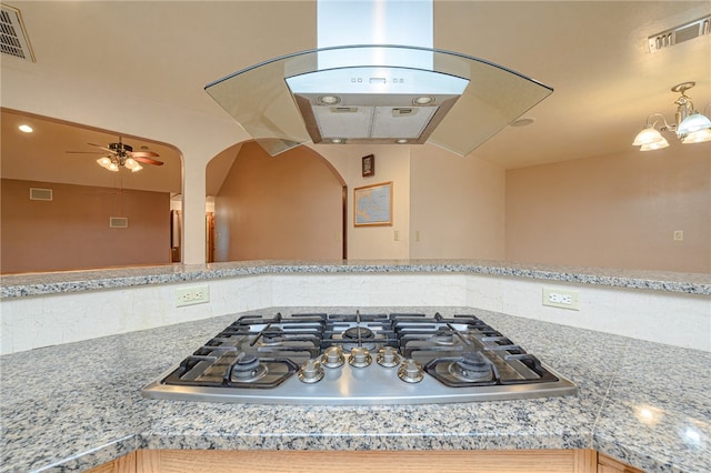 kitchen with stainless steel gas cooktop, ceiling fan with notable chandelier, and ventilation hood