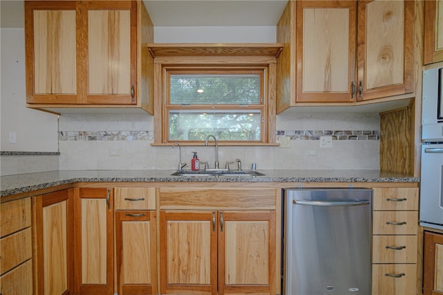 kitchen featuring tasteful backsplash, stainless steel dishwasher, sink, and light stone countertops