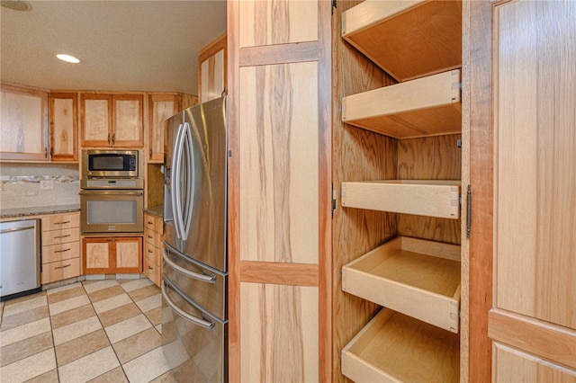 kitchen with light brown cabinets, light stone counters, and appliances with stainless steel finishes