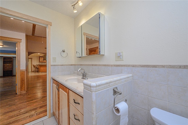 bathroom with hardwood / wood-style floors, vanity, toilet, and tile walls