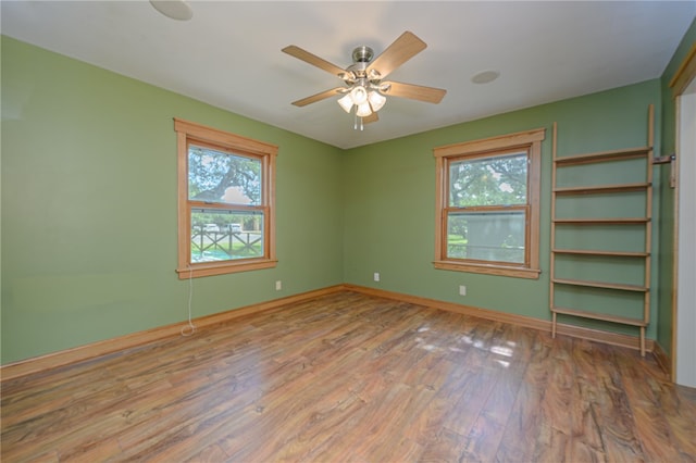 empty room with hardwood / wood-style floors, a healthy amount of sunlight, and ceiling fan