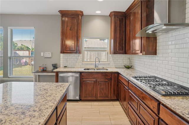 kitchen featuring stainless steel appliances, wall chimney range hood, sink, and decorative backsplash