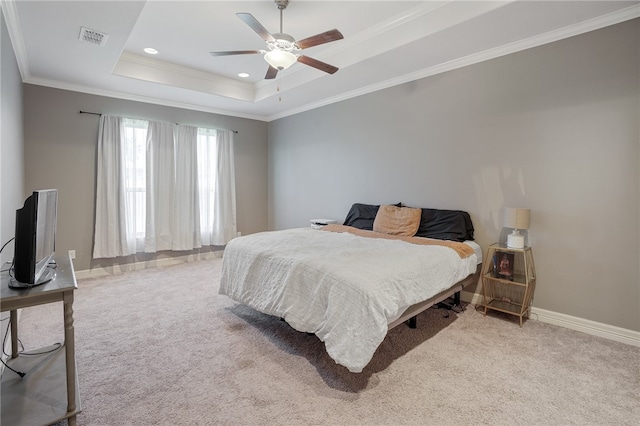 carpeted bedroom featuring ceiling fan, crown molding, and a tray ceiling