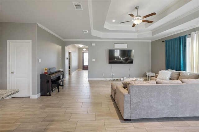 living room with ornamental molding, ceiling fan, and a tray ceiling