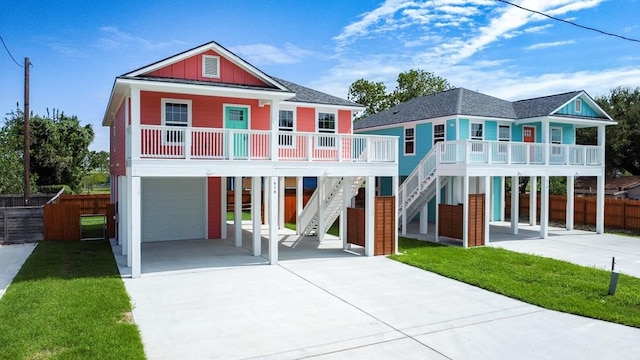raised beach house with covered porch, concrete driveway, an attached garage, and a carport
