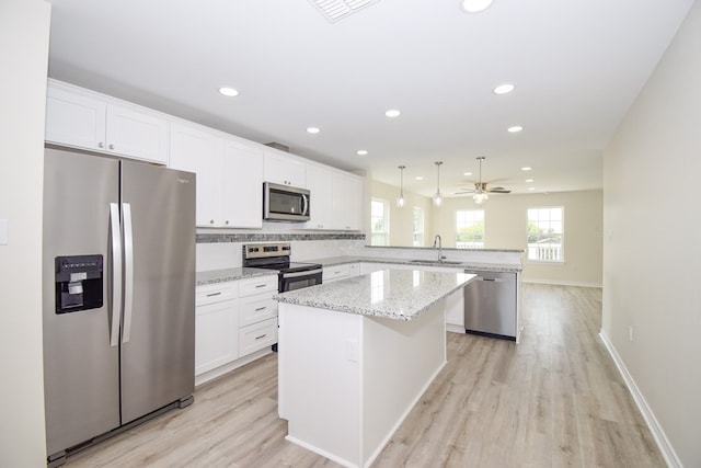 kitchen featuring stainless steel appliances, hanging light fixtures, sink, white cabinets, and a center island