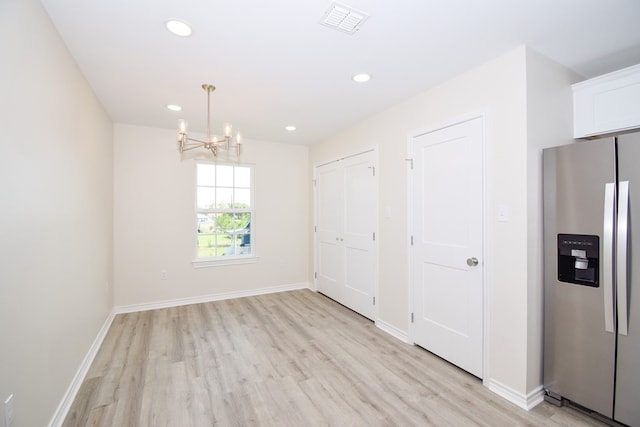 unfurnished dining area with light wood-type flooring and a chandelier