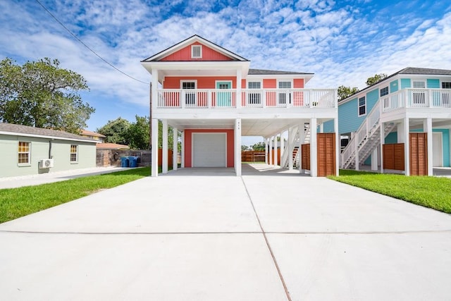 raised beach house featuring a carport, stairway, driveway, an attached garage, and covered porch