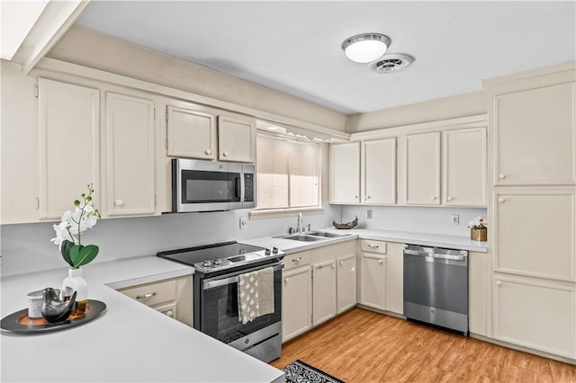 857 Belmeade Dr, Corpus Christi, TX 78412 - kitchen featuring stainless steel appliances, a sink, light countertops, light wood-style floors, and white cabinetry