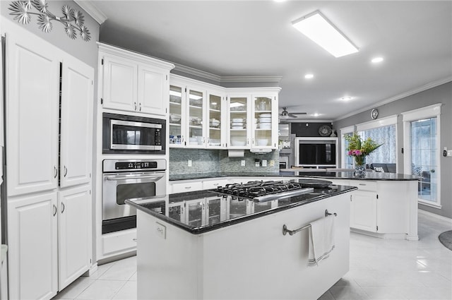 4705 Grand Lake Dr, Corpus Christi, TX 78413 - kitchen featuring appliances with stainless steel finishes, a kitchen island, crown molding, light tile patterned floors, and white cabinetry