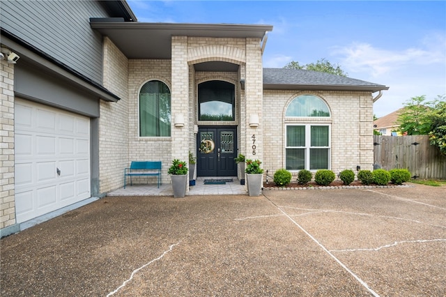 4705 Grand Lake Dr, Corpus Christi, TX 78413 - property entrance featuring brick siding, asphalt driveway, roof with shingles, and a garage