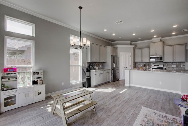 kitchen featuring light hardwood / wood-style flooring, hanging light fixtures, gray cabinets, backsplash, and appliances with stainless steel finishes