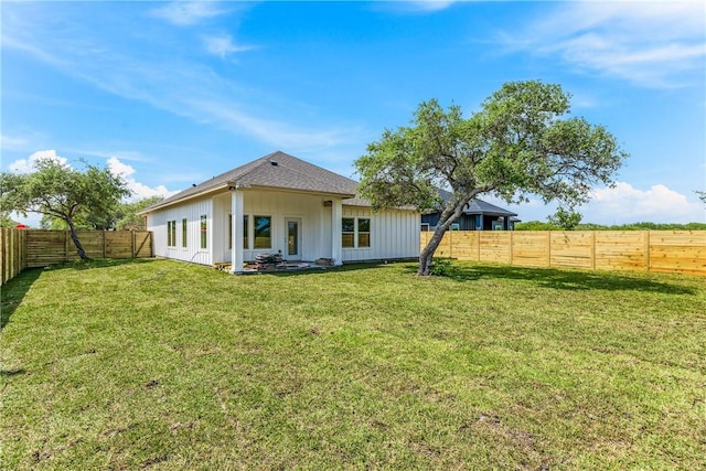 rear view of house with a fenced backyard, board and batten siding, and a yard