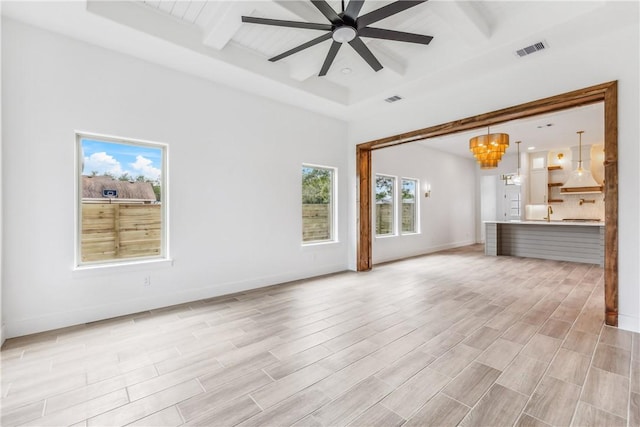 unfurnished living room with beam ceiling, ceiling fan with notable chandelier, light wood-style flooring, and visible vents