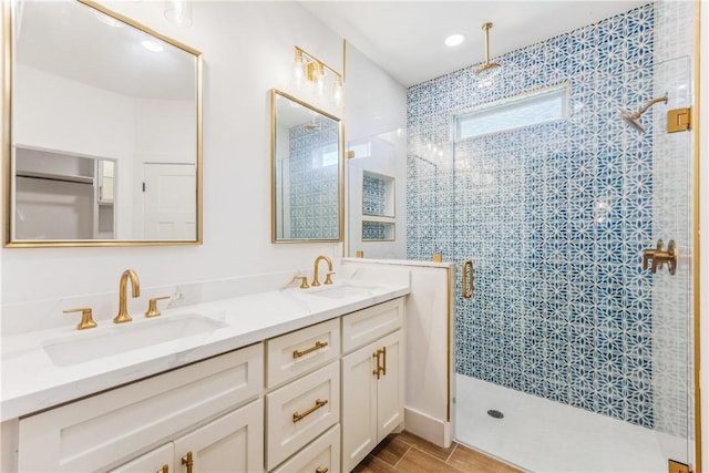 bathroom featuring double vanity, a sink, a stall shower, and wood finished floors