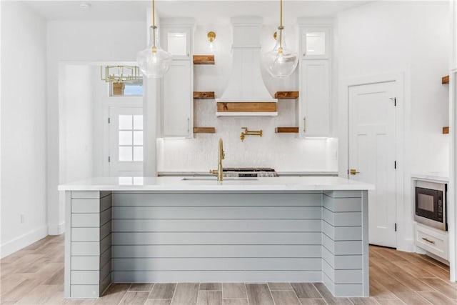 kitchen featuring open shelves, black microwave, light wood-style floors, light countertops, and white cabinetry