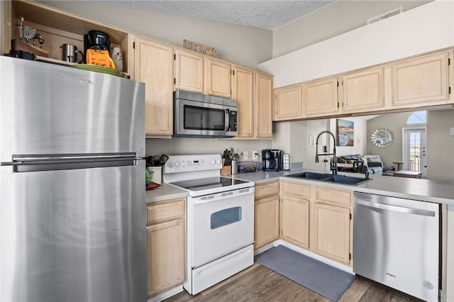 kitchen featuring dark hardwood / wood-style floors, light brown cabinetry, lofted ceiling, sink, and stainless steel appliances