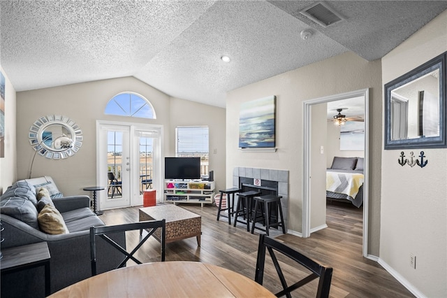 living room featuring dark wood-type flooring, ceiling fan, vaulted ceiling, and a textured ceiling