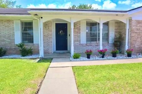 doorway to property with a yard and covered porch