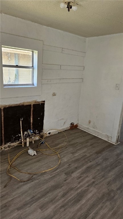 empty room with a textured ceiling and dark wood-type flooring