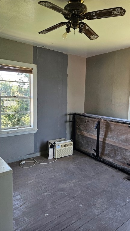 empty room with a wall unit AC, a ceiling fan, and dark wood-style flooring