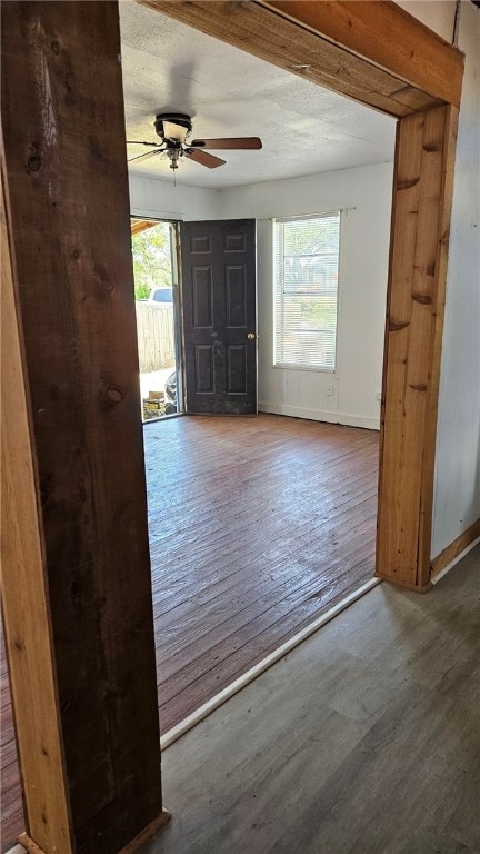 entrance foyer with a ceiling fan, a textured ceiling, baseboards, and wood finished floors