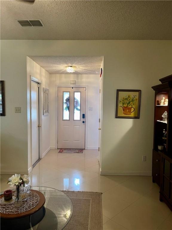 2237 Sunset Cliff Dr, Ingleside, TX 78362 - foyer entrance featuring a textured ceiling, light tile patterned flooring, and baseboards