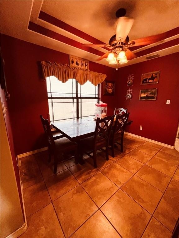 unfurnished dining area with tile patterned flooring, a tray ceiling, and ceiling fan