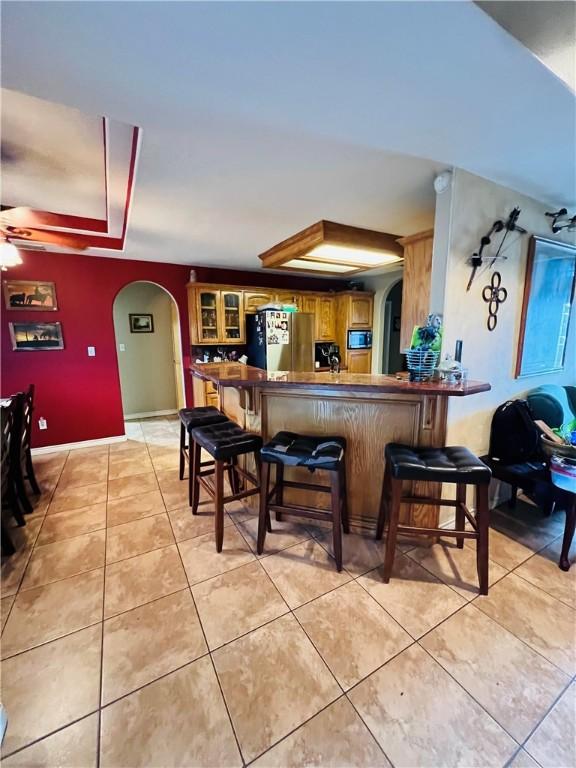 bar featuring built in microwave, stainless steel fridge, ceiling fan, and light tile patterned flooring