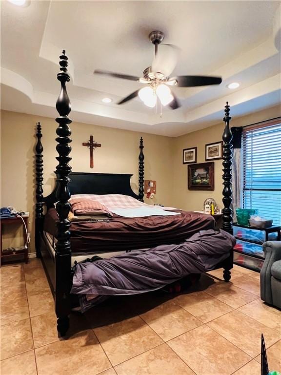 bedroom featuring ceiling fan, light tile patterned floors, and a tray ceiling